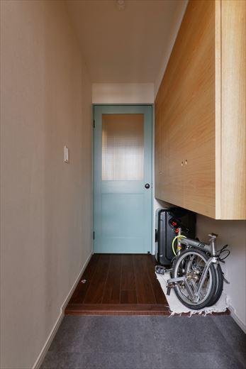 折り畳み自転車やスーツケースを置くため、靴収納はフロートタイプに。その手前にハンガーパイプが取り付けられており、雨に濡れた上着や傘などが掛けられる。お気に入りの本を手に出かけられるよう、ドア脇にはブックホルダーも。
