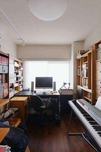 もともと書斎として使っていた居室。お手持ちの本棚やラックをここに集め、リビングはお気に入りだけの空間に。背後の収納は扉を撤去して一部をクロゼット、一部はタンス置き場とした。既存エアコンの移設にあたり、ダクトを天井に這わせてうまく隠している。