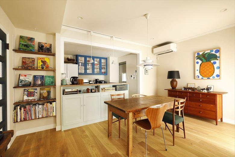 ダイニングはキッチンと併せて「見せる」空間に。マガジンラックに飾った洋書やお気に入りの絵、吊り戸棚のブルーが素敵なアクセント。天井や開口部の縁まわりにはAさんご家族がアメリカで暮らした家のようにモールディングを施した。