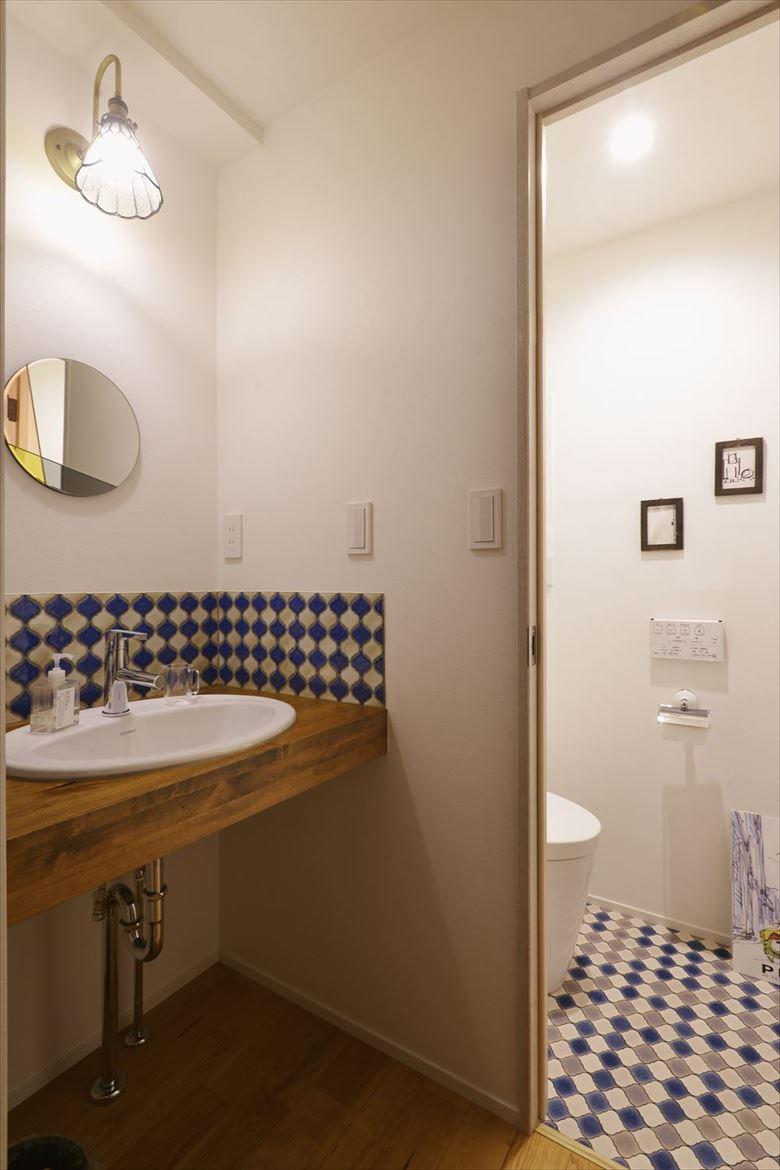 2階に造作した手洗いカウンターは来客用を意識してお洒落な印象に。タイルはトイレと色味やデザインを寄せて統一感を演出。丸鏡やブラケットも可愛らしい。「気に入ったタイルが廃番で使えなかったときにも、プランナーが好みに合ったアドバイスをしてくれました」
