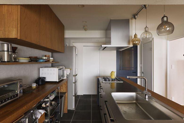 キッチン背面はお気に入りのスチールシェルフがぴったり収まるカウンターを造作。
キッチン奥の扉の向こうは洗面室