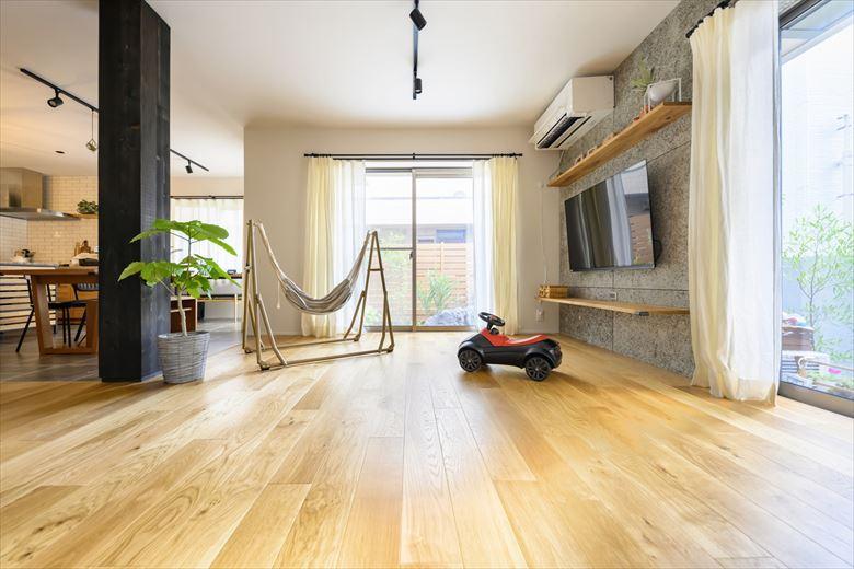 テレビ側の壁にあしらった木毛セメント板でラフな雰囲気に