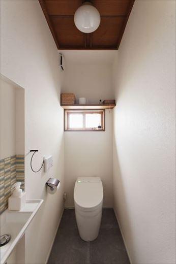 小窓から光が入り込む明るいトイレ。手洗いスペースのカラフルなタイルがアクセントに。