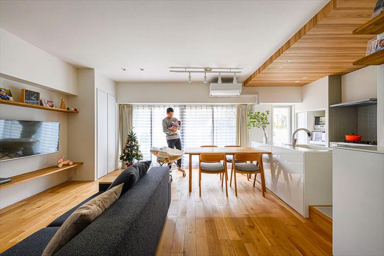 床は無垢のオーク。テレビがある壁面にはシンプルな棚を造作。キッチンは配置の変更に伴い床を一段上げ、その中に配管を通している。