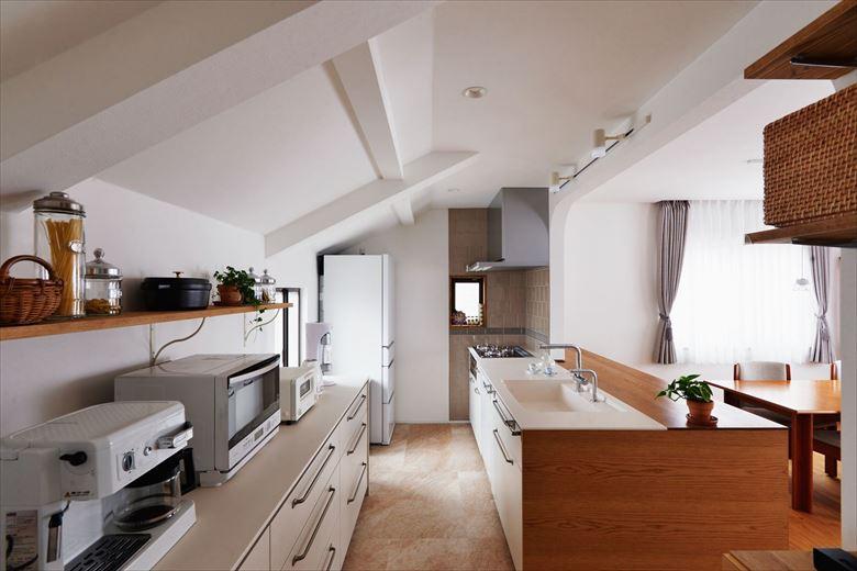 天板が造作家具とフラットでつながったオープンキッチンは、扉に空間が明るくなるよう白色を採用。背面収納も同シリーズでそろえて一体感を。