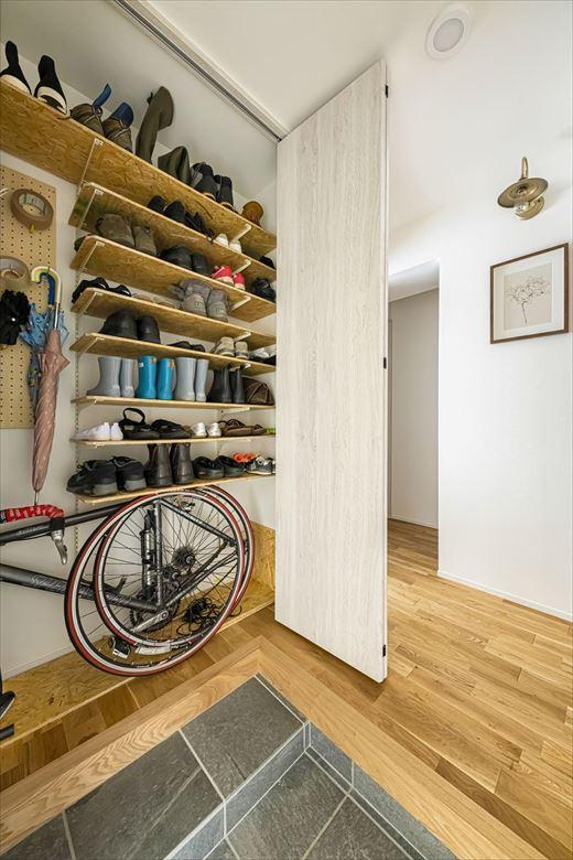 玄関ホールの収納。天井ぎりぎりまでスペースを生かし、靴や自転車など収納できるようにした