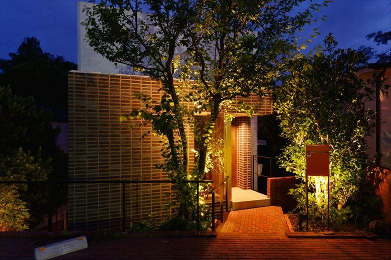 夜にはスポットライトでシンボルツリーをはじめとした木々が浮かび上がる。非日常を感じられるエントランス