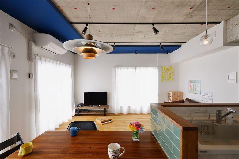 既存の和室を取り込んで広々とした空間に生まれかわったリビング。コンクリートを現しにし、一部ブルーでアクセントを。床はホワイトオークの無垢材をセレクト