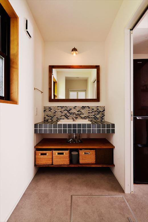 キッチンとつなげて家事をしやすくするために水廻りはレイアウトを変更。洗面室とバスルームの位置を入れ替え、脱衣室のスペースもゆったりと。新たに設けた洗面台は造作。シンプルなデザインにこだわって選んだタイルを贅沢に使った