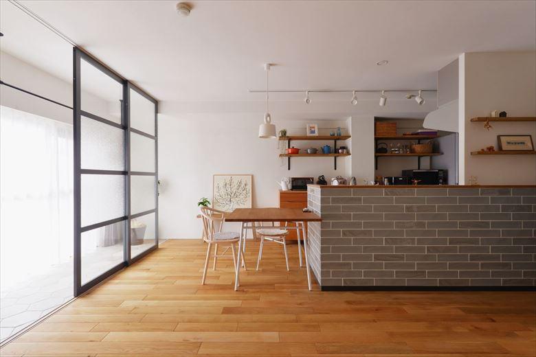 隣の和室を取り込み、孤立していたキッチンは向きを変えてオープンな対面式キッチンに。光がたっぷりと差し込む開放的なLDKとなった。床はオーク無垢フローリング。壁は珪藻土を採用。キッチンのタイルは、マット素材と光沢素材を組み合わせて張り、タイル使いにもこだわった