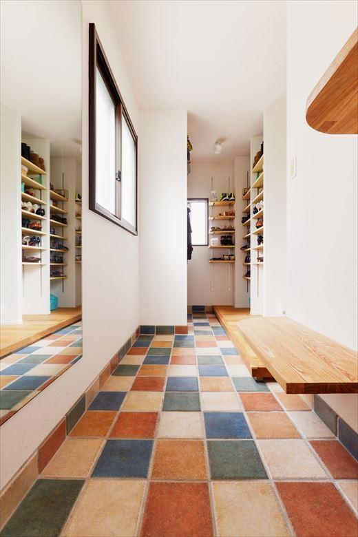 玄関は土間スペースを広げ、浴室だった空間にSICを新設。靴収納だけでなく、コート掛けも用意した。ドアを開けるとカラフルなタイルが広がり明るい印象に