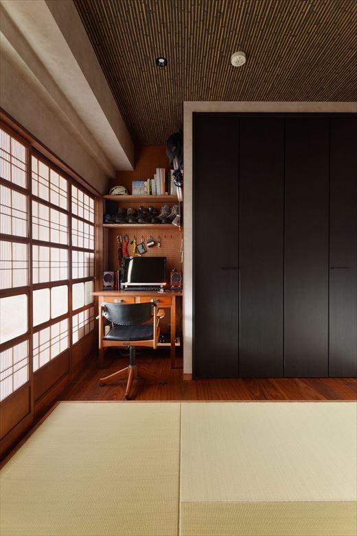 寝室は布団派のお2人のため、一部畳敷きに。黒の収納建具や竹を編んだような天井クロスで和の趣を感じられる空間。一角には旦那さま用のワークスペースを設けた