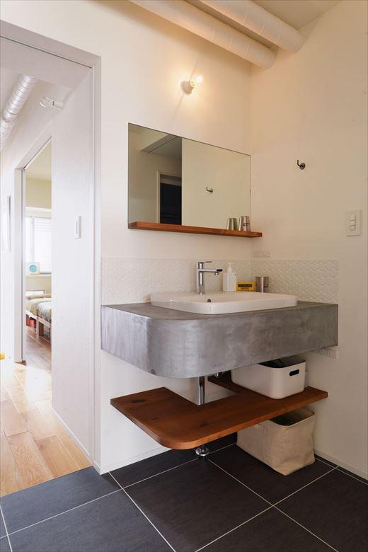 玄関側からリビングドアを開けた左横にオープンな洗面スペースを配置。帰宅時にすぐ手を洗うことができるだけでなく、来客時にも気兼ねなく使ってもらえる。角を落とした丸みのあるフォルムやモルタル調の仕上げなど、想い描いていたイメージをカタチにした