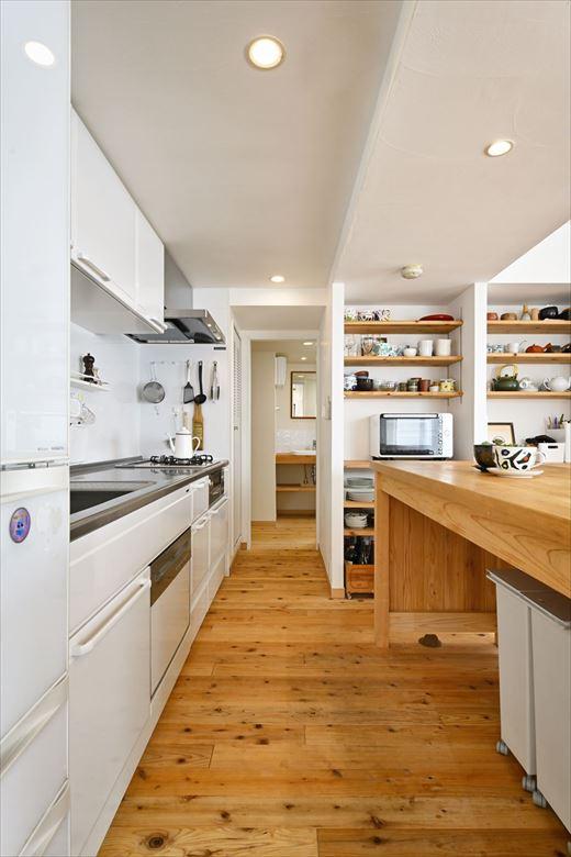 以前のお住まいも壁付けキッチンで使いやすかったため、今回もL字型から壁付けに変更。背面にお持ちのキッチンカウンターを設置した。壁面には食器や家電などが置けるオープン棚を造作。棚板も杉を使っている