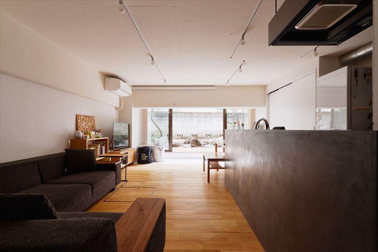 大きな梁で暗かった南側の居室の間仕切りを取り払い、明るい陽射しが部屋の奥にまで届くようになった。庭側はスペースを広げ、大きなテラス窓をつけてサンルームを設けた。サンルームからウッドデッキへとつながり、屋外と屋内に一体感がうまれた