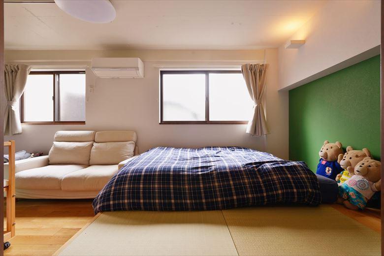 畳&布団派のご主人たっての希望で寝室は小上がりの畳敷きを採用。下部は収納になっている。壁の一面は落ち着いたグリーンのクロスと間接照明でくつろぎの空間に。間続きの洋室は将来の子ども部屋。仕切れば個室にすることができる