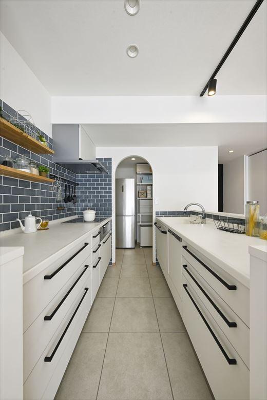 キッチンは90度向きを変えリビングと対面に。シンクとコンロを前後に分けたⅡ型を採用することで、２人で立ってもゆとりがあるキッチンスペースに。生活感を感じる冷蔵庫などはパントリーに隠してスッキリと