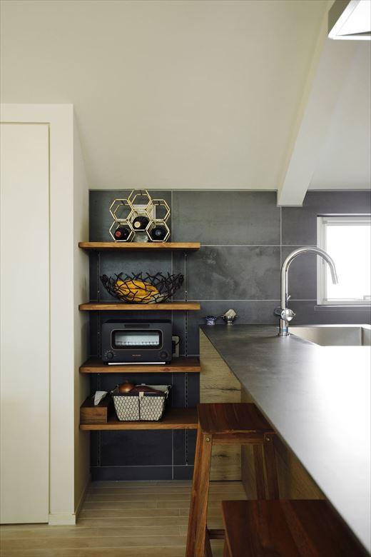キッチンの背面とサイドにオープン棚を設置。無垢の床やキッチンの木目と調和する棚板。サイド側は置くものに合わせて高さが調節できる可動棚に