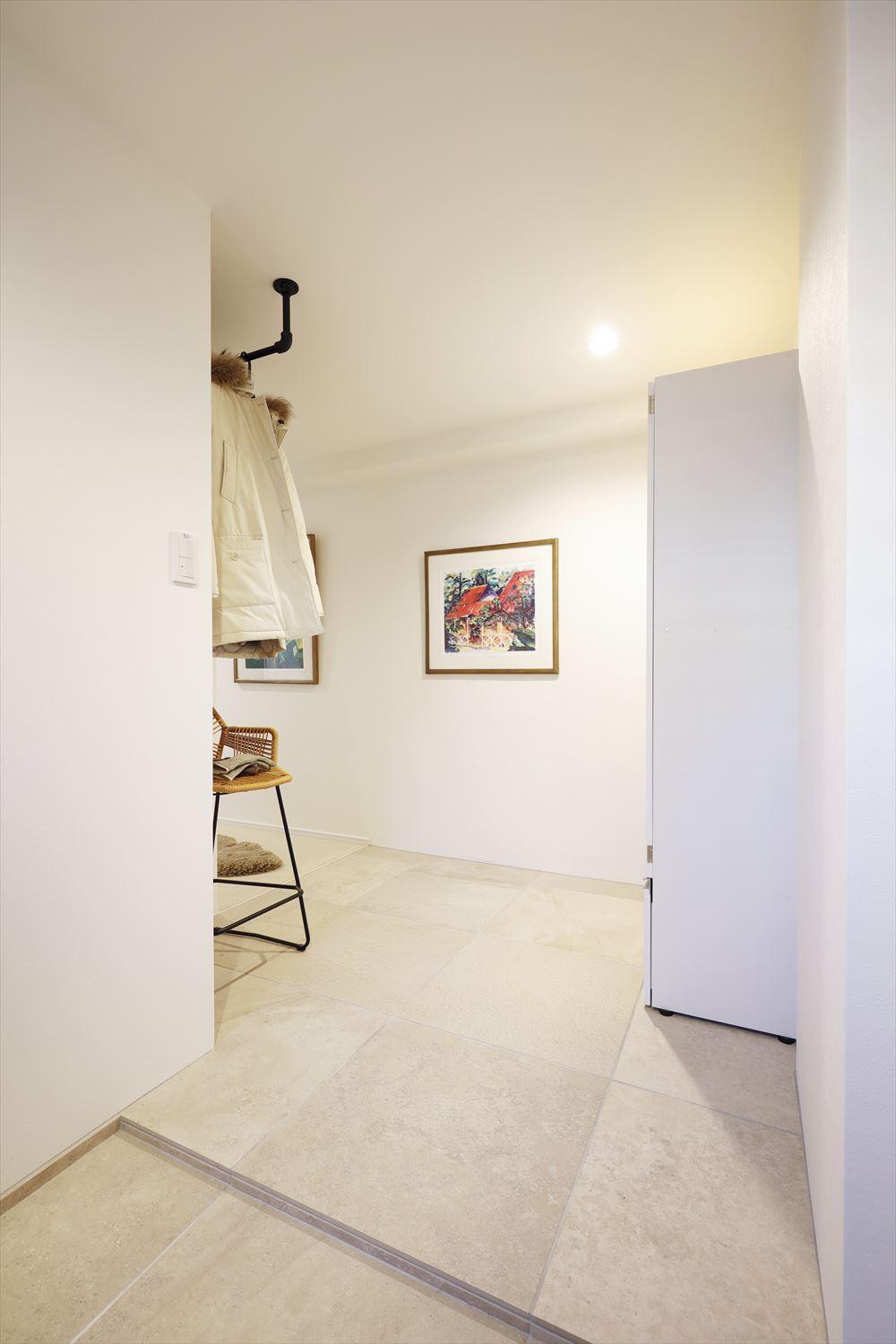 玄関土間と廊下は同じ磁器タイルを貼った。一部、ホールを拡大してコートなどが掛けられるハンガーパイプを取り付けて便利に