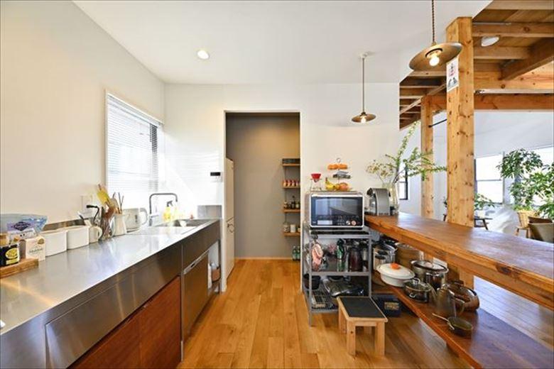 キッチンは壁付けに。ダイニング側には収納も兼ね備えた造作の作業台を設置した。壁付けキッチンでもオープンなので家族とコミュニケーションを取りながら、料理が楽しめる。奥のパントリーには食品類だけだなく冷蔵庫も配置できるので、生活感を隠してすっきり