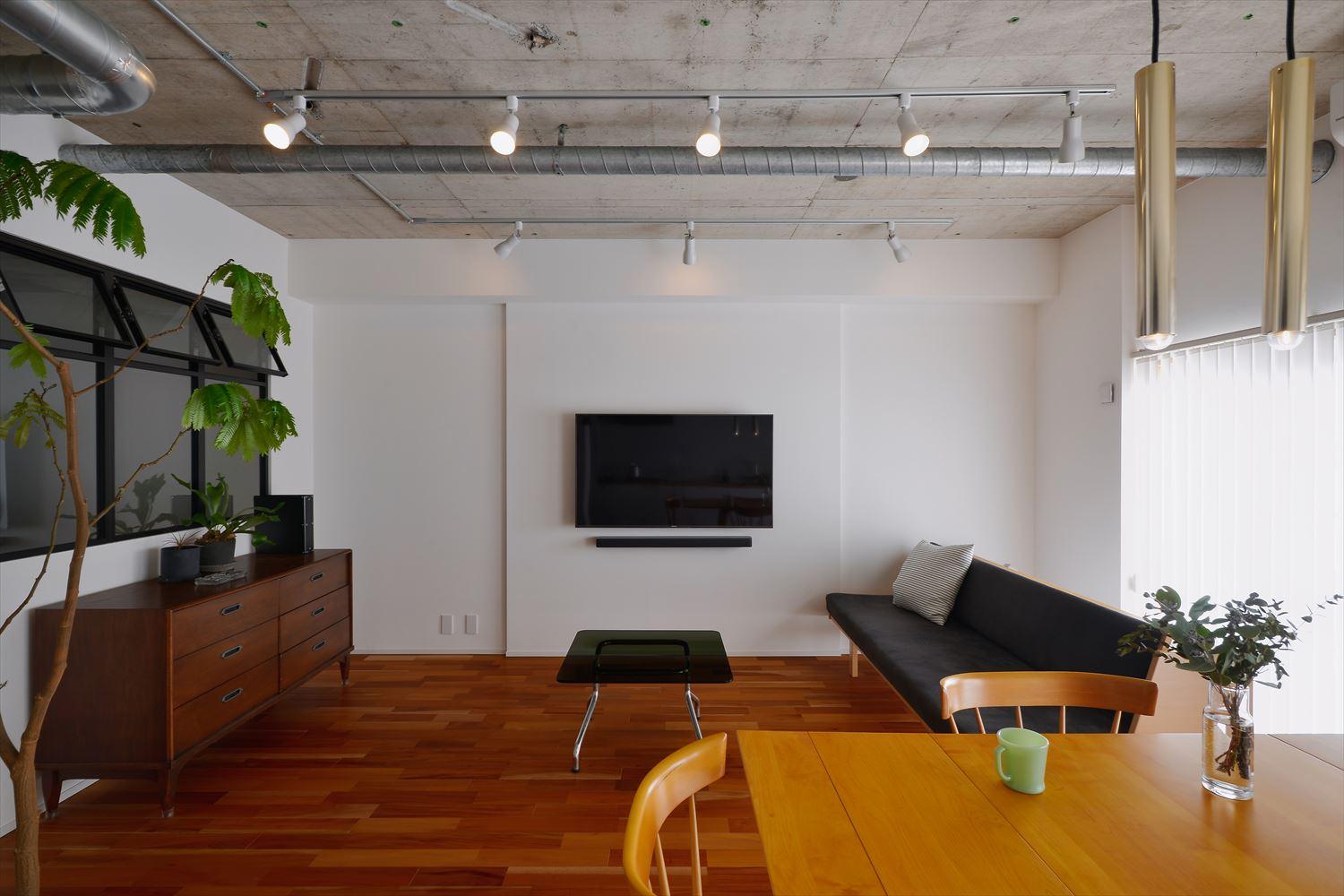 壁はシンプルな白いクロス。床はやや赤みのあるマホガニーの無垢材。床の色合いとあらわしにした天井の無骨さがビンテージ家具の表情を引き立たせる空間に。ダイニングテーブルは、愛用のものを家具屋さんに修理してもらって再利用。