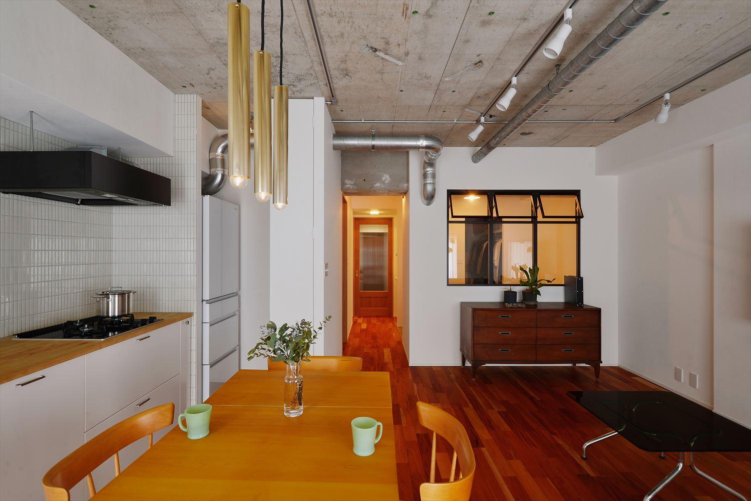 キッチンは白を基調としたシンプルなデザインのものをセレクト。リビングをより広く確保するため、壁付けに。リビングと寝室を仕切る壁に設けた室内窓は、黒いフレームが空間に引き締まった印象を与えてくれる。