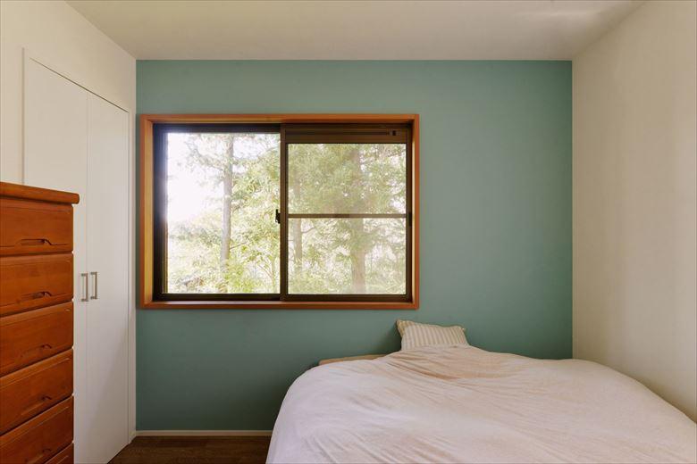 ブルーグリーンのアクセントクロスがさわやかな印象の寝室