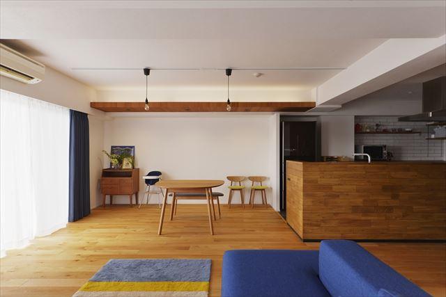 フローリング材を貼ったキッチンカウンターやダイニング側の間接照明を入れた下がり天井はご夫妻がやってみたかったこと。真っ白な空間と木目でまとめたシンプル＆ナチュラルな空間を奥様のお好きなブルーが爽やかに彩ります。