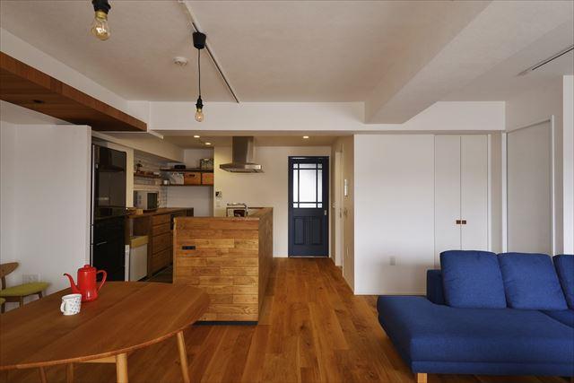 閉塞感のあったキッチンの仕切り壁を撤去してキッチンを移動。開放的で一体感のあるLDKを実現した。リビングドアは引き戸に交換し、ブルーで塗装。空間のアクセントに。ソファ後ろのリビング収納は、ご主人のアイデアで洗面からも使えるマルチ収納に