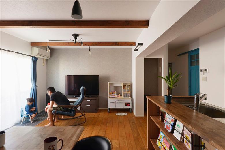 マンションの2戸をつなげたリノベーション。LDKと水廻りは1戸分を使用して広々と。栗皮塗装で使い込んだような色合いに仕上げた無垢フローリングや米松の化粧梁で、ご希望だった木造戸建てのような雰囲気に。掃出し窓の手前はタイルを敷いてインナーテラスのように室内干しや植物などを置くことができる