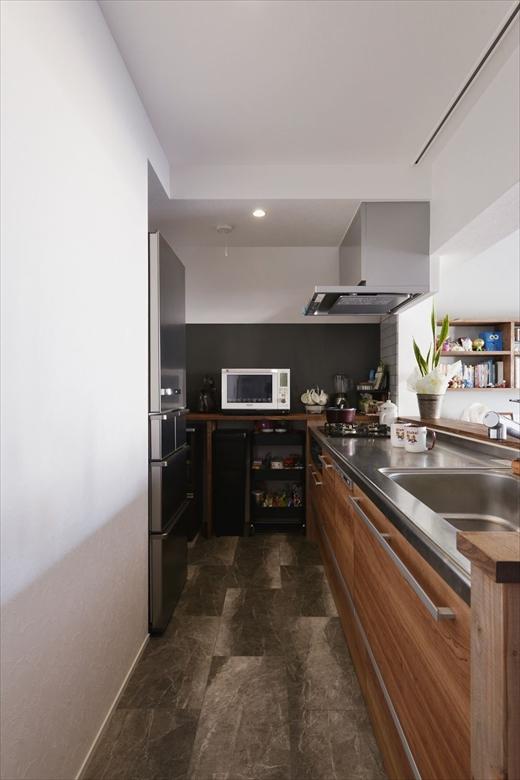 インテリアになじむ木調デザインの対面キッチンからは、リビング・ダイニングで遊ぶお子さんの様子を見守れる。フロアタイルや側面の壁には黒を使ってシックな印象に仕上げた