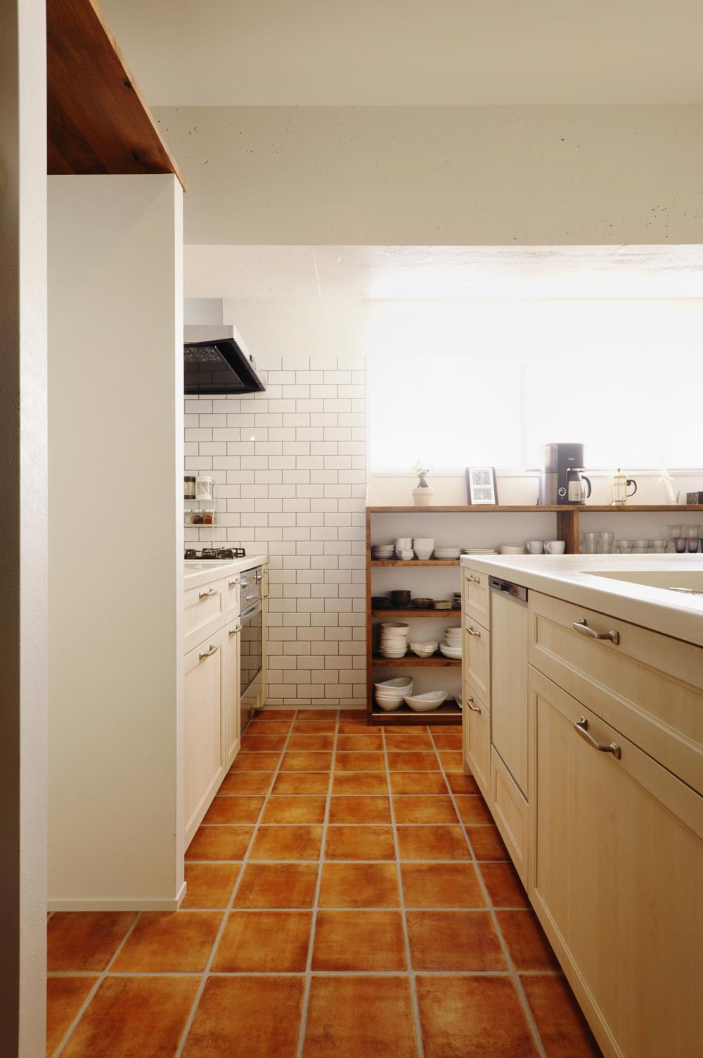 壁で仕切られ独立していたキッチンはオープンに。壁側にコンロ、対面側にシンクがあるⅡ型タイプ。キッチンは優しい色味の框扉が気に入ってMさんが選んだ製品を採用した。床は水まわりのお手入れがしやすいフロアタイルを。窓側には、窓の位置に合わせて食器棚を造作した