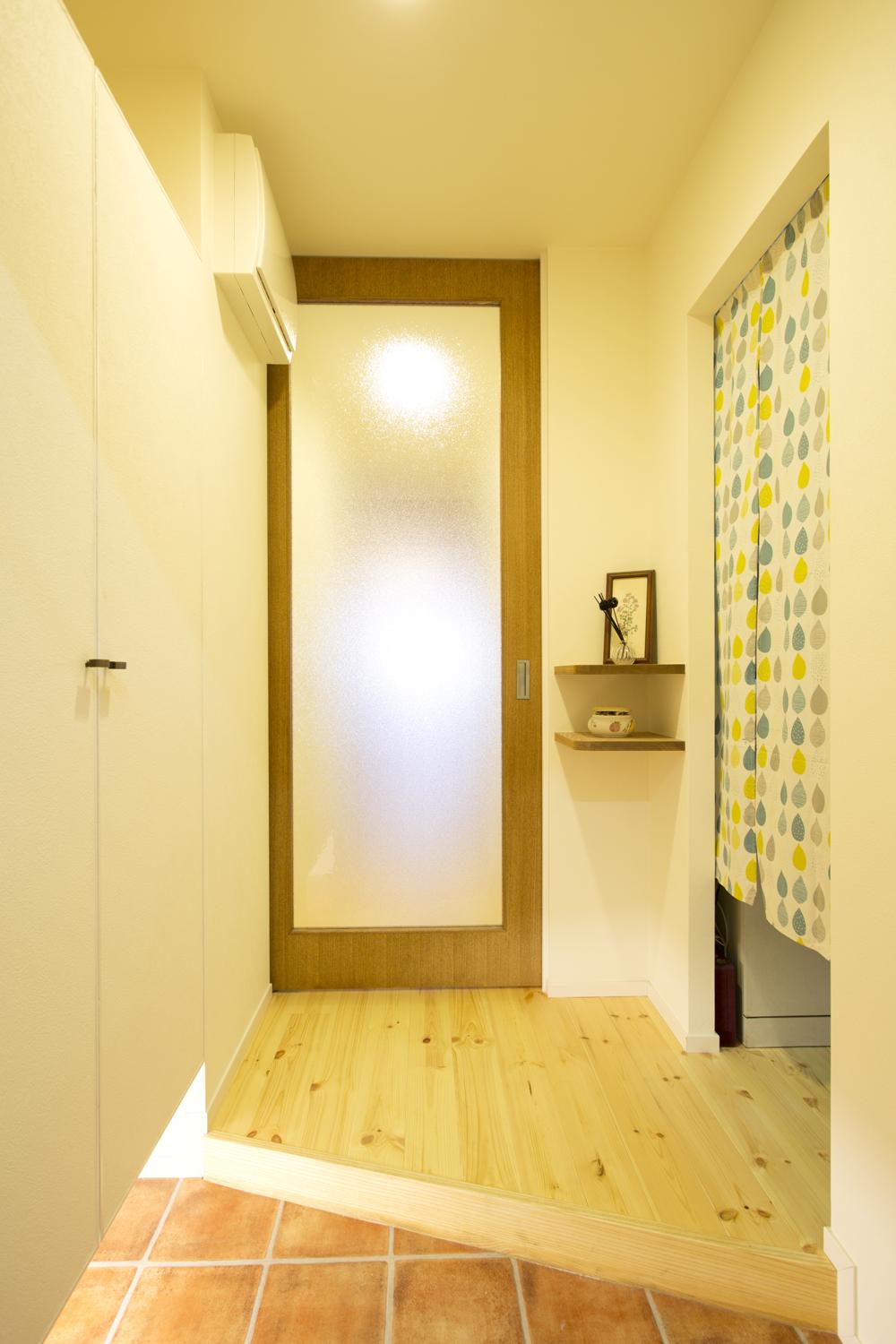 玄関は向きを変えてリビングとまっすぐつながるように。リビング入り口の建具は光が通るように大きなガラスを入れた。開け放つと左側の壁にすっぽりはまって壁の一部となるのもポイント。左側には下足収納を、右側には家族みんなの服を収納できる大容量のウォークインクロゼットを造作。