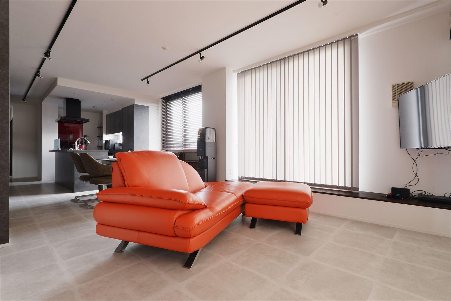 シンプルでモダンなリビングにオレンジのソファがアクセント。
床はリビングと同じくお手入れしやすいフロアタイル。白い壁や奥のグレーの壁ともなじんでいる
