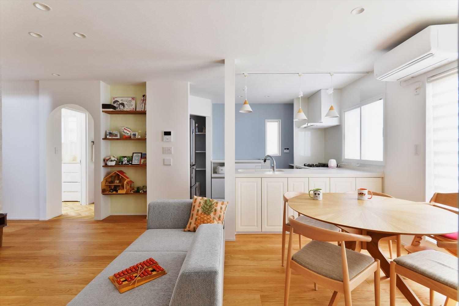 キッチンの仕切り壁を取り払って一体感のあるLDKに。白と木目をベースにしたシンプル&ナチュラルな内装＋水色のクロスがアクセント。