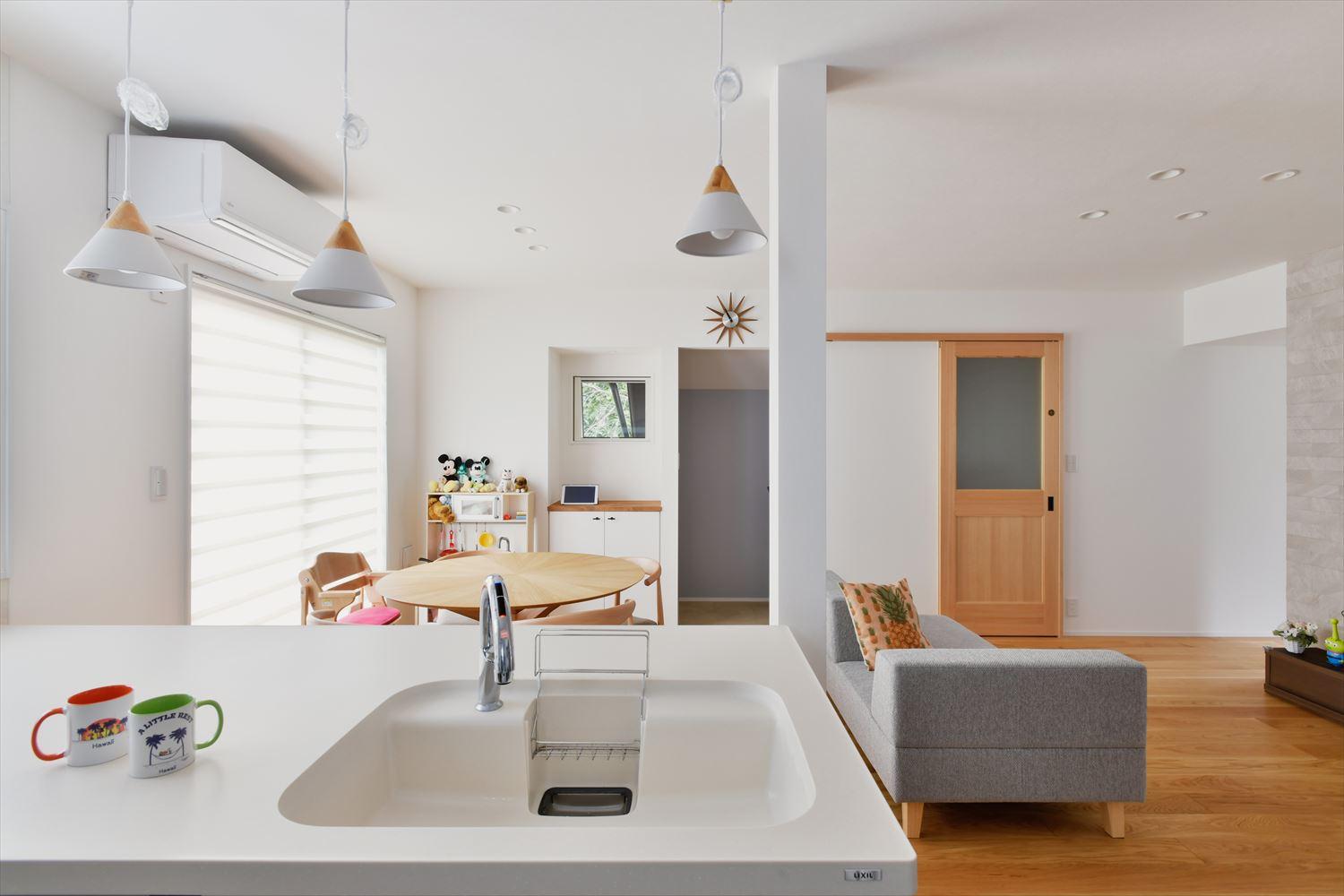 キッチンからはリビングダイニングが見渡せる。現しになった柱やペンダントライトも白で塗装してシンプルな空間に。正面の開口は書斎コーナー