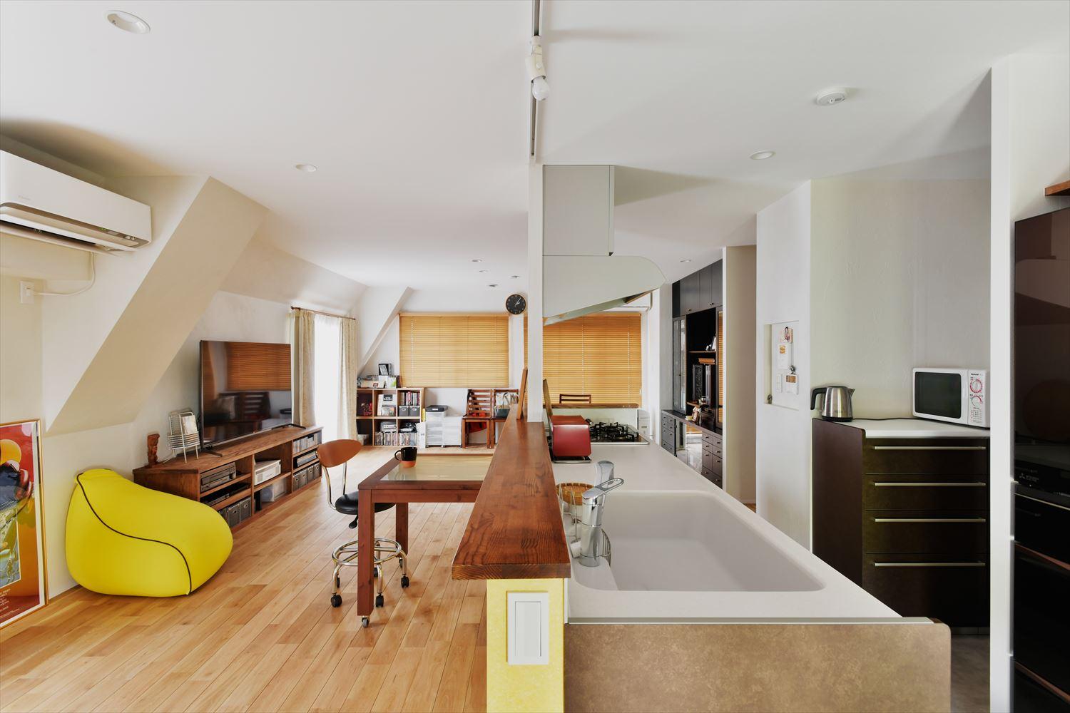 西側でそれぞれ独立していたキッチン・リビング・ダイニングをバルコニーがある東側へ大きく移動してひとつの広々とした空間に。キッチンカウンターに採用した黄色のアクセントが気持ちまで明るくしてくれる。床はナラ無垢フローリング。壁は珪藻土。