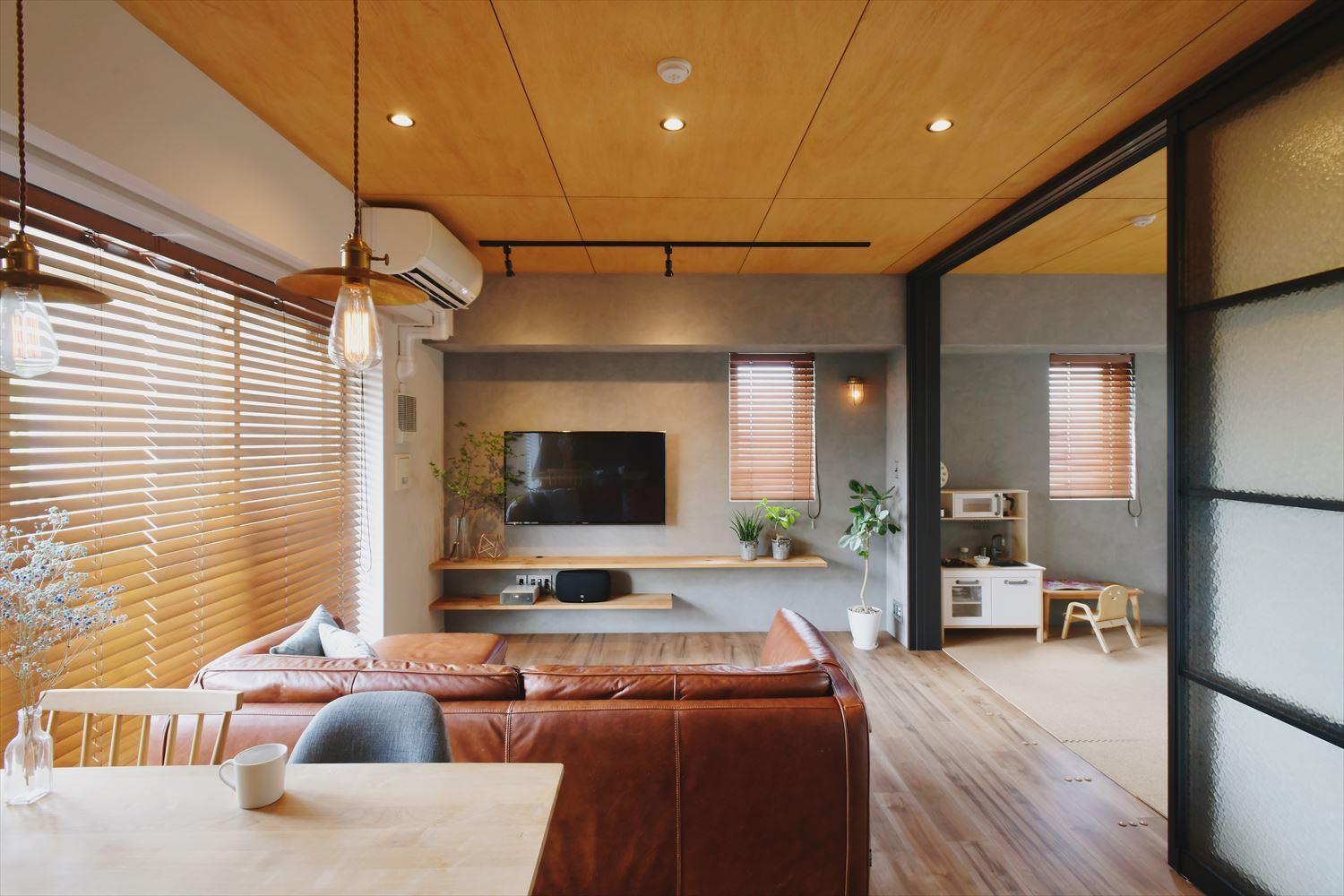 テレビ側の壁面はコテ塗りのヘイムスペイントを採用。隣接する洋室は将来リビングと一体で使うことを想定し、同じ仕上げに。壁掛けテレビ&壁内配線でスッキリと。天井のライティングレールや交換したブラックの建具が空間を引き締めている