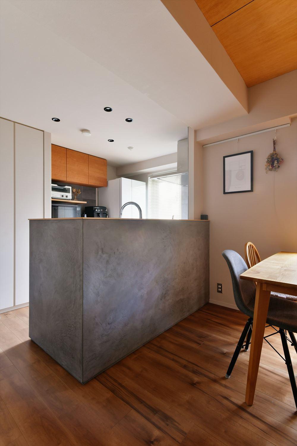 キッチンは手元が隠れるカウンターを設け、テレビ側の壁と雰囲気を合わせたモールテックスで仕上げた。立ち上がりがあることで生活感を見せないというメリットも
