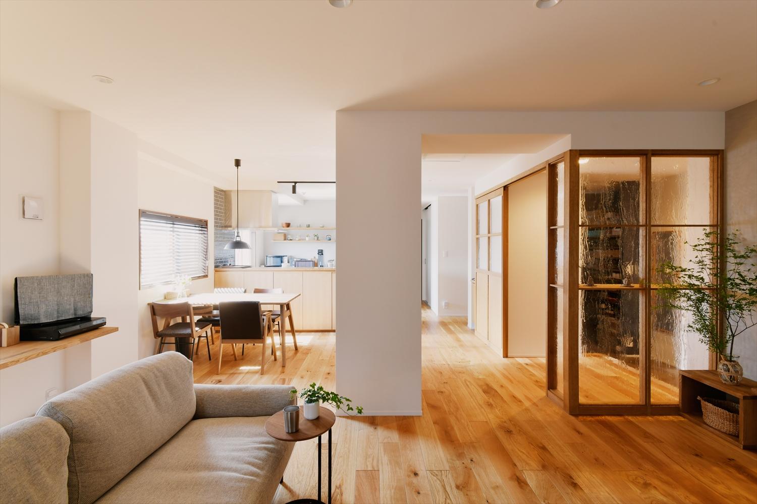 玄関ホールから直接LDKへ。仕切りには造作のガラス戸や格子ガラスを用いて、玄関ホールにも光が入るようにした。
LDKの床は床暖房対応のオーク三層フローリング。造作の建具などのナチュラルな木目を活かしながら、アクセントクロスやキッチンタイルにグレー系を用いて落ち着きのある雰囲気に