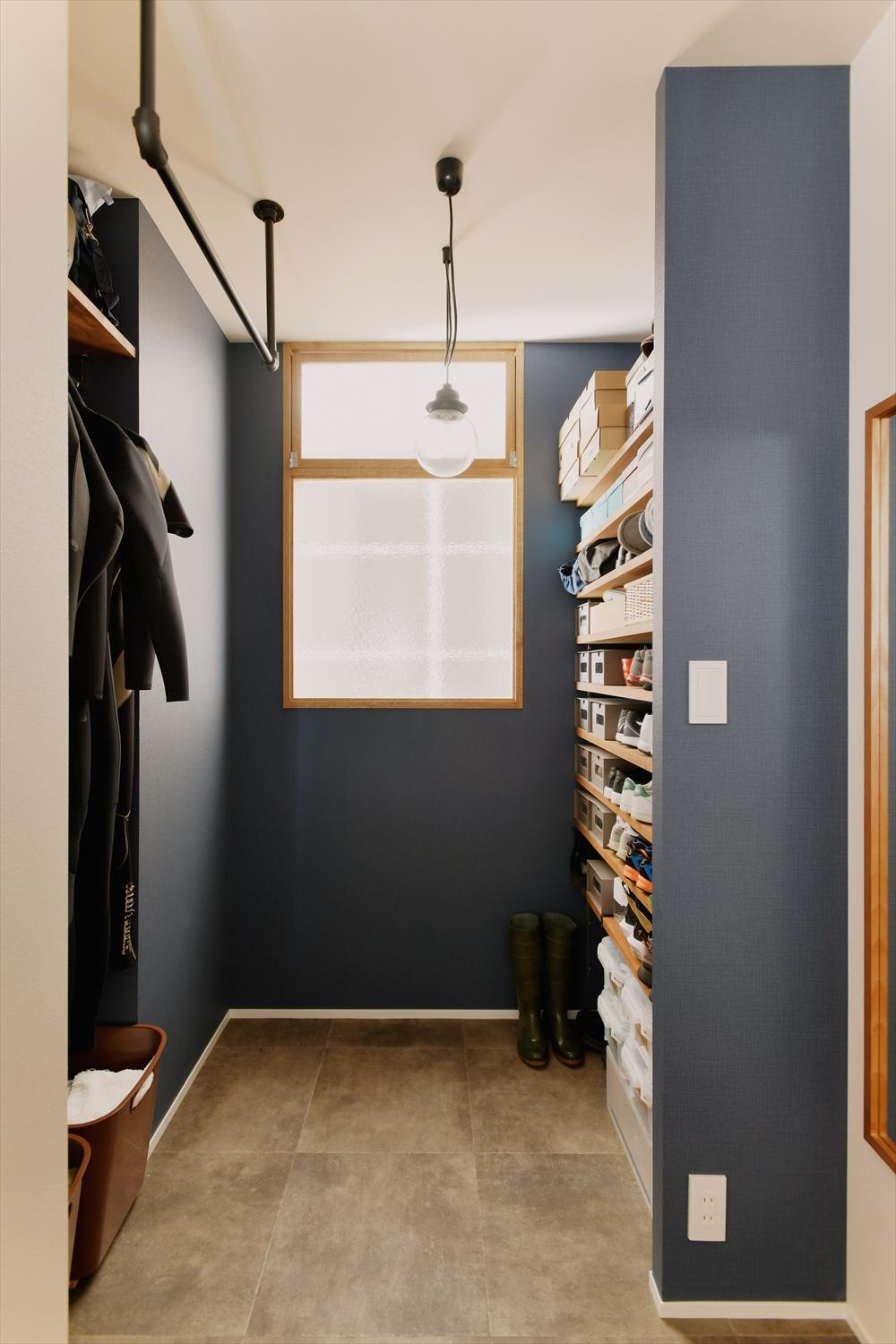 玄関にはシューズインクローゼットを。趣味のサーフィン用具をしまうスペースや上着などが掛けられるハンガーパイプを設置。窓のない廊下やトレーニングルームに光と風を届ける室内窓も設置した