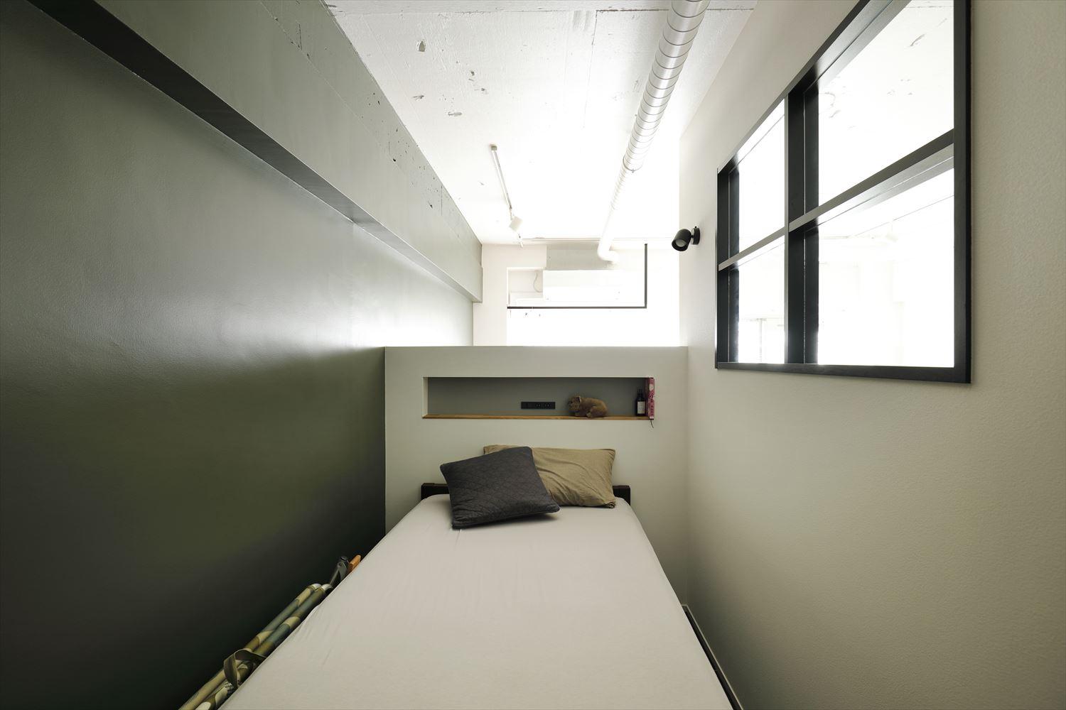 ミニマムな空間に抑えたベッドコーナー。室内窓や腰壁でゆるく仕切り、LDKと繋がりつつ、プライベートな空間に。