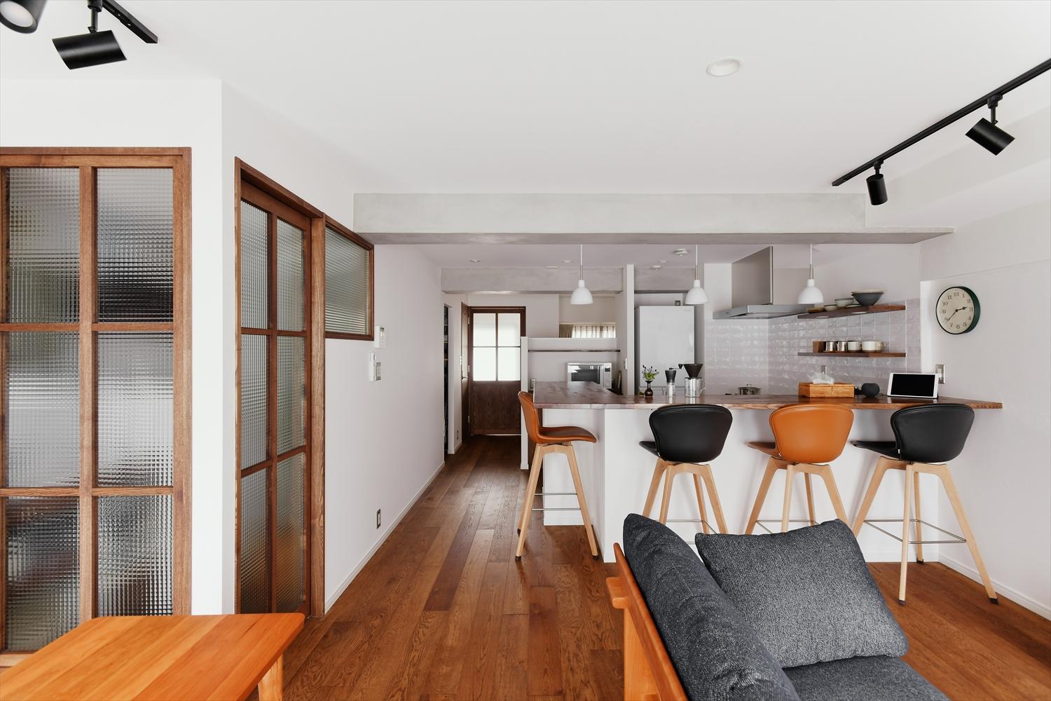 ベランダ側にあった２つの居室とDKを一体化してもうけた広々と明るいLDK。写真左手、ガラス入りの建具や室内窓を取り付けた空間は洗面脱衣室。バルコニーからの光が届く明るい水回り