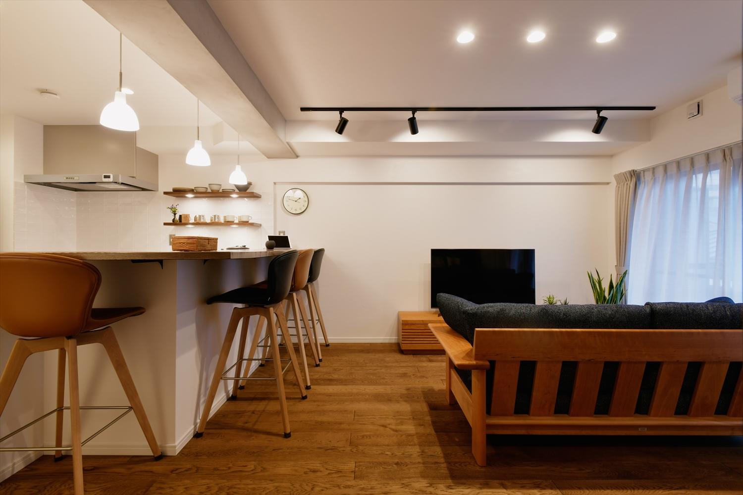 リビングはダウンライトやスポットライトでくつろげる照明に。TV背面の壁は珪藻土を左官。珪藻土の調湿作用・消臭効果で心地よく過ごせる。キッチンのスツールは購入するものを事前に決められていて、それに合わせてLDK全体の内装をコーディネート。