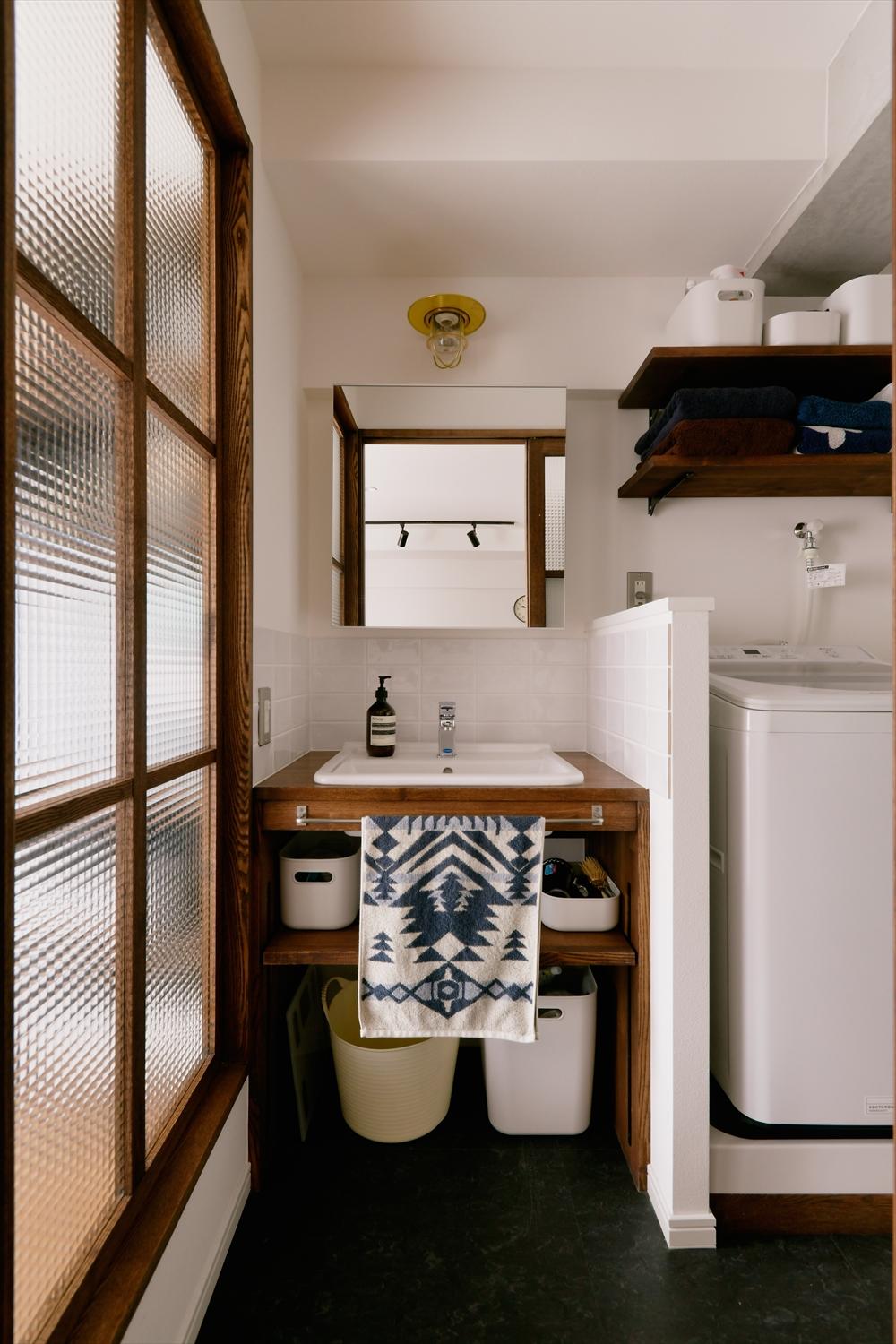 既存の位置では光が届かなかった水回りは窓側へ移動。チェッカーガラスを使った建具や室内窓からたっぷり光が入る明かるい空間に。シンプルなデザインの洗面台は造作。