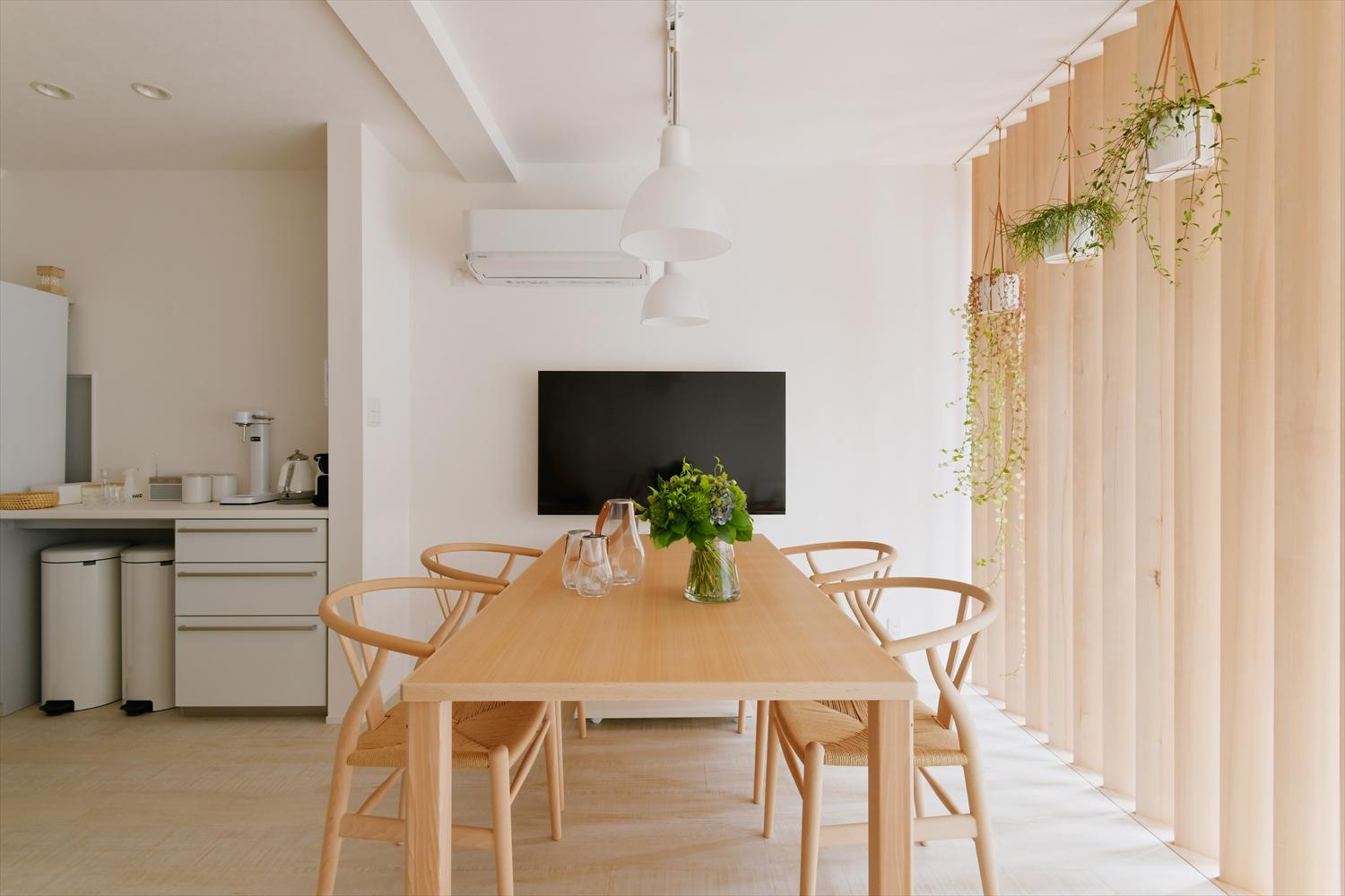 全面ガラス張りの道路側からの光が柔らかく入るダイニングスペース。外からの視線を遮る縦格子のパーティションで、プライバシーを保ちつつ、明るさも確保した