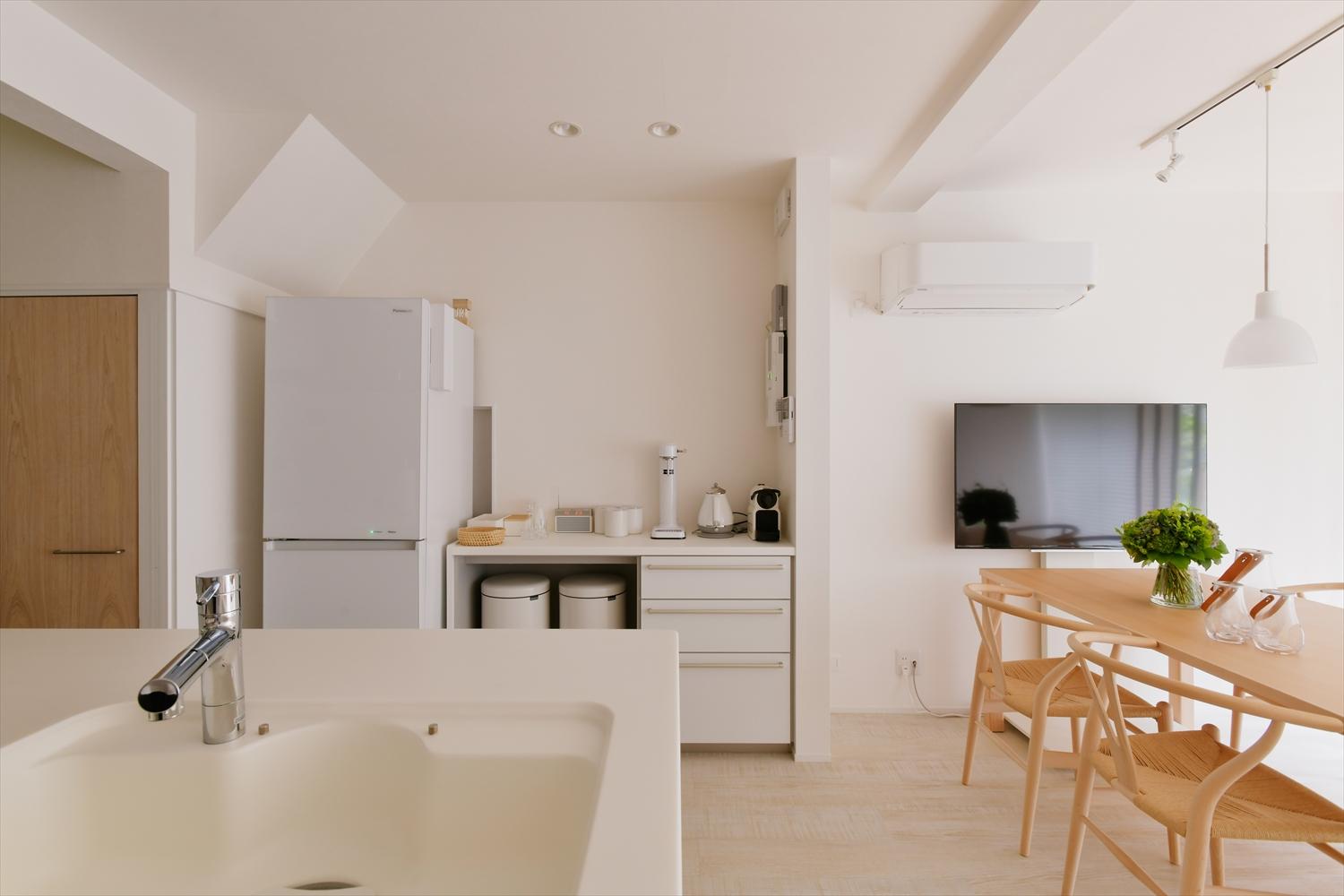 白を基調にしたダイニング・キッチン。ダイニングテーブルや格子の明るい木目でナチュラルな雰囲気に
