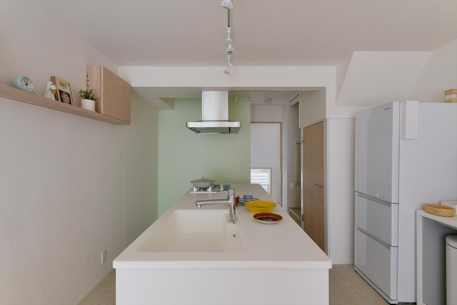 四方から囲めるフラットカウンターのアイランドキッチン。お料理教室にピッタリ。奥のグリーンのクロスは娘さんのチョイス。白基調の空間にアクセントを