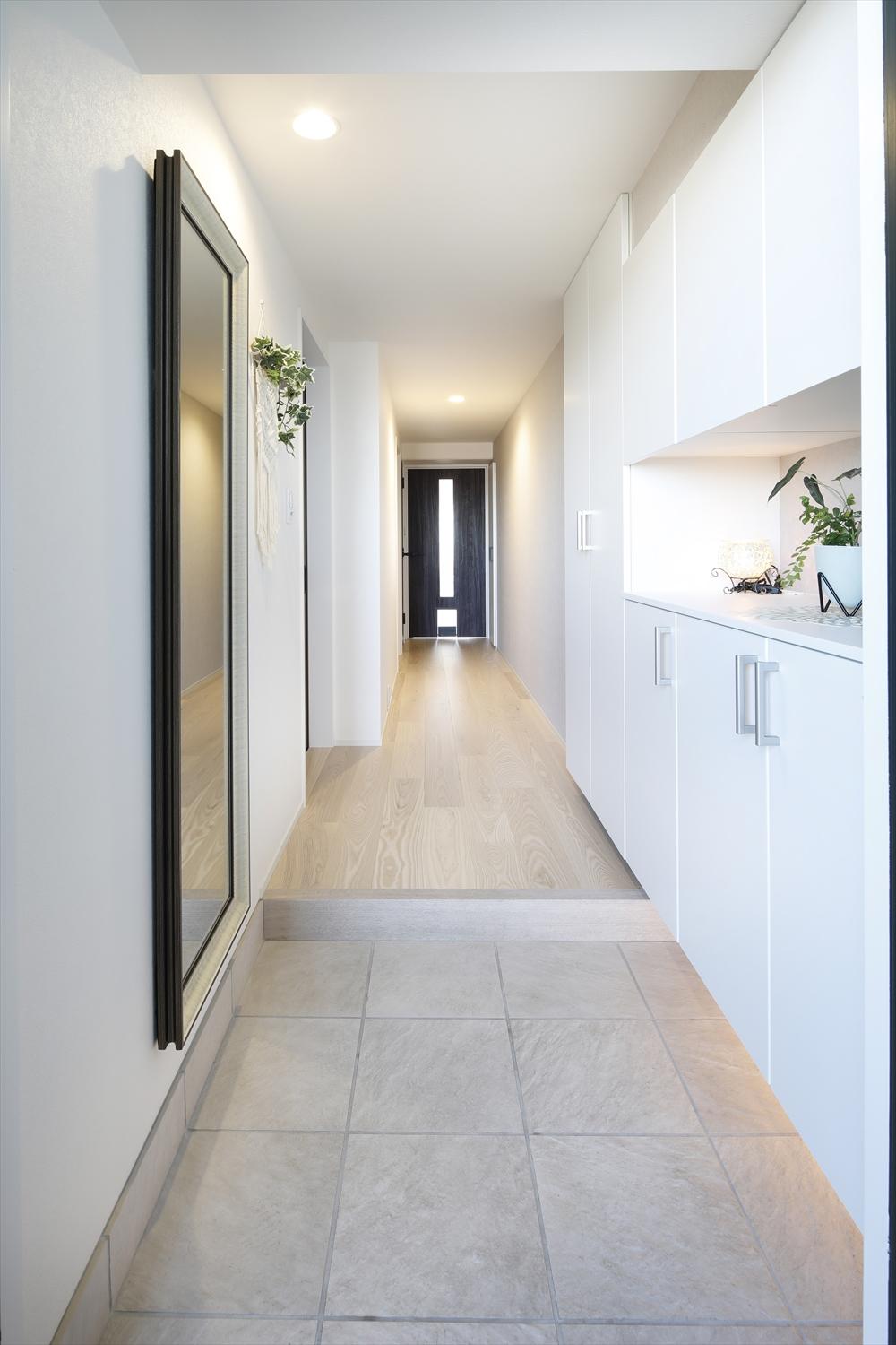 白を基調にしたスッキリと清潔感のある玄関＆廊下。奥のリビングドアが空間のアクセントに。