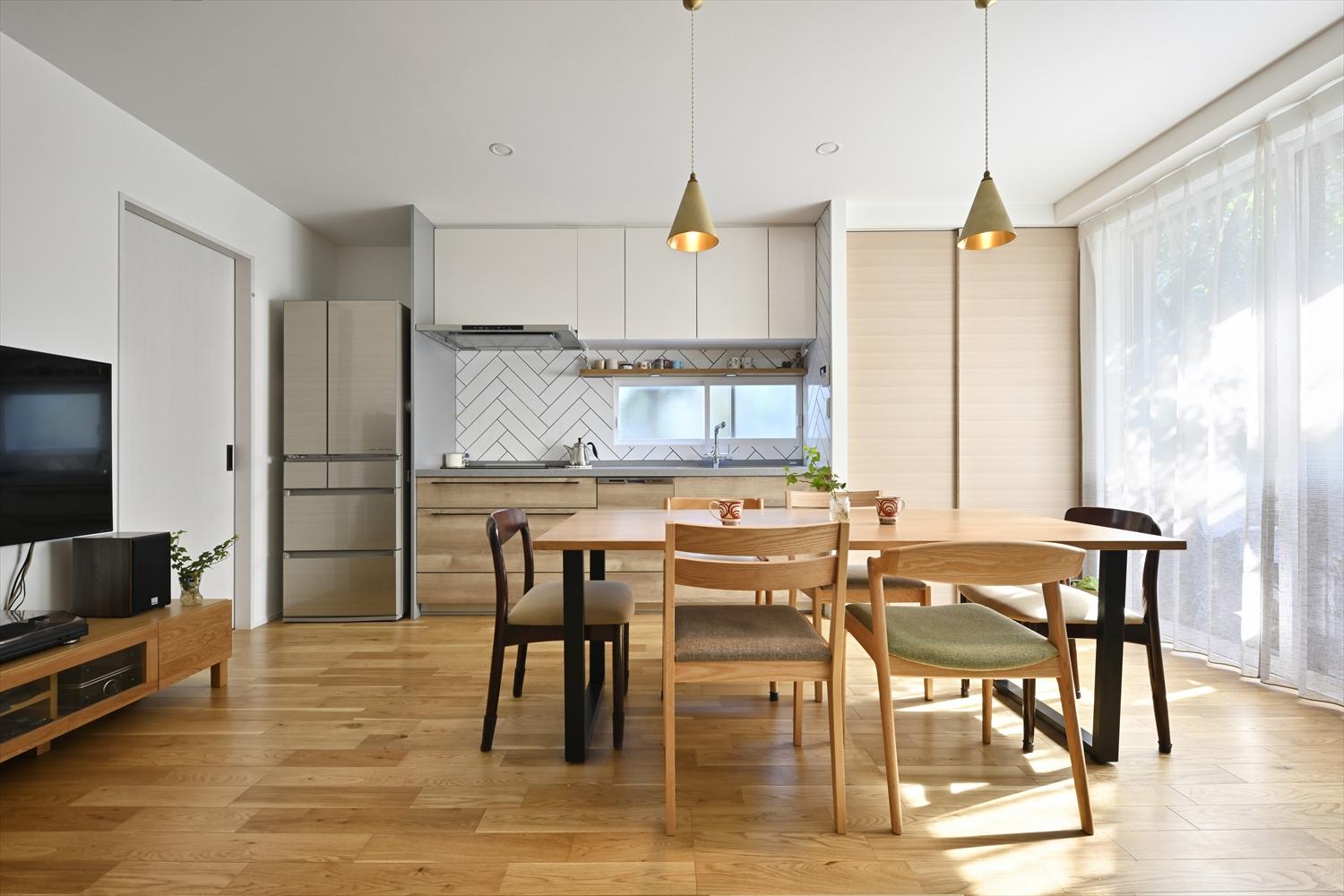 引き戸を開けると、玄関から正面に見えるキッチンは、設備やタイルにこだわった。キッチン右手の天井まで届く収納は、扉で隠してスッキリと。限られた範囲でも容量のある収納でオープンキッチンをいつでもキレイに保てる